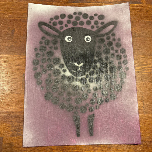 A square art print or card featuring a stylized black sheep face and body made of dots on a dusty purple background, photographed on a brown wooden surface.